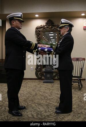 Le Capitaine Ron Ravelo, gauche, commandant du USS ABRAHAM LINCOLN (CVN 72), présente un drapeau pour le Cmdr. Dreama Parsons au cours de sa retraite. Parsons a servi à bord de l'Abraham Lincoln comme officier de systèmes de combat et la retraite après 32 années de service naval. Banque D'Images