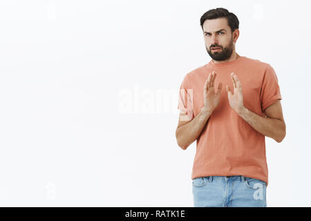 Guy refusant d'essayer d'être repas farci, tenant les mains près de poitrine dans le rejet et aucun geste, se détourner avec dégoût dégoûté et grimace étant réticents, ne veulent pas faire plus d'action suggérés mur gris Banque D'Images