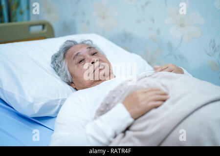 Les personnes âgées ou vieille dame femme sourire patient face lumineuse avec forte santé tout en étant allongé sur le lit dans la salle de l'hôpital de soins infirmiers en santé : médecine. Banque D'Images