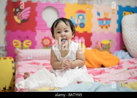 Asie un bébé heureux sur le lit de bébé / enfant rire face à ouvrir la bouche et clap / beautiful baby girl smiling cute adorable expressifs heureux bébé col Banque D'Images