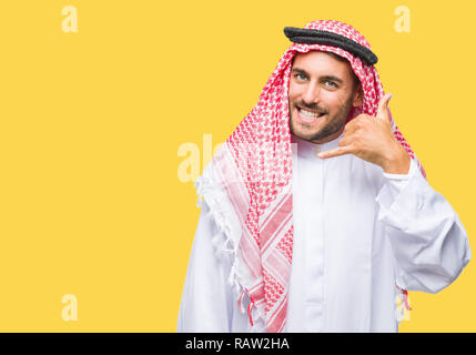 Beau jeune homme portant un keffieh sur fond isolé faisant sourire téléphone geste avec la main et des doigts comme parler au téléphone. Communic Banque D'Images