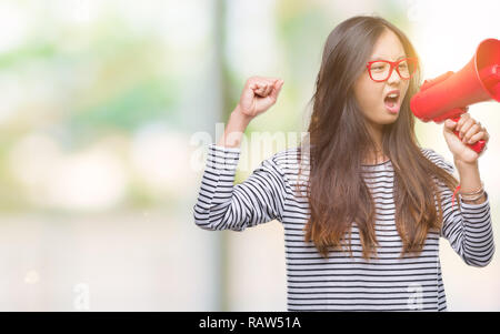 Young Asian woman holding megaphone sur fond isolé contrarié et frustré de crier avec colère, fou et hurlant de main levée, la colère con Banque D'Images