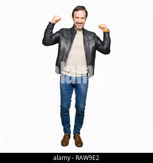L'âge moyen bel homme vêtu de noir veste en cuir montrant les muscles des bras fier sourire. Concept de remise en forme. Banque D'Images