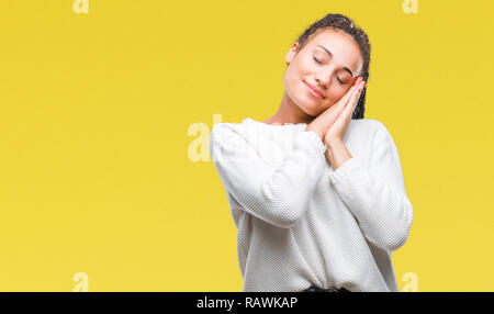 Les jeunes cheveux tressés african american girl wearing winter sweater sur fond isolé fatigué dormir rêver et posant avec les mains ensemble tout en Banque D'Images