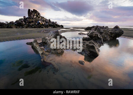 Un lever du soleil sur la plage de Shag Rock ci-dessus à Christchurch en Nouvelle-Zélande Banque D'Images