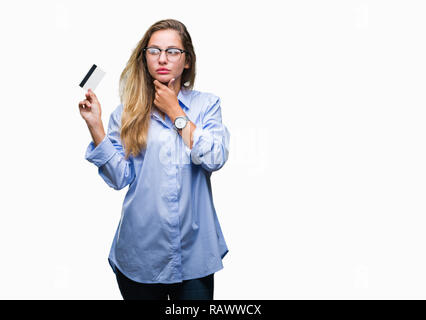 Jeune belle blonde woman holding credit card sur fond isolé visage sérieux de penser à question, idée très confus Banque D'Images