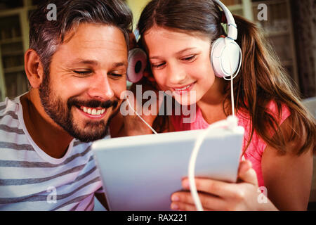 Père et fille à l'écoute de la musique sur tablette numérique Banque D'Images