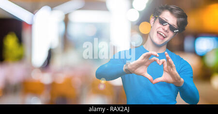 Jeune homme portant des lunettes plus drôle thug life fond isolé smiling in love montrant le symbole de coeur et la forme des mains. Concept romantique. Banque D'Images