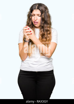 Belle Jeune femme portant un t-shirt blanc souffrant de douleur sur les mains et les doigts, l'inflammation de l'arthrite Banque D'Images