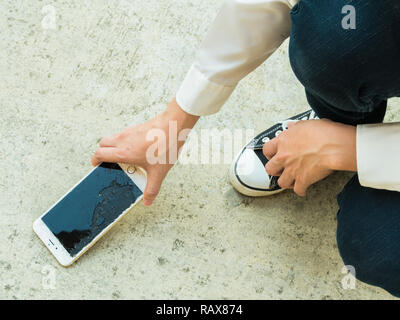 Personne qui casse Téléphone intelligent (écran fissuré) du sol Banque D'Images