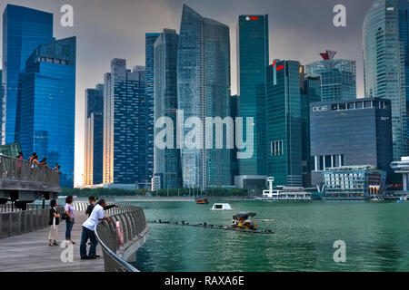 Pendant le coucher du soleil et sous les nuages de mousson sombre, poussettes profitez de la vue sur Marina Bay, Singapour, le quartier des banques à l'arrière-plan Banque D'Images