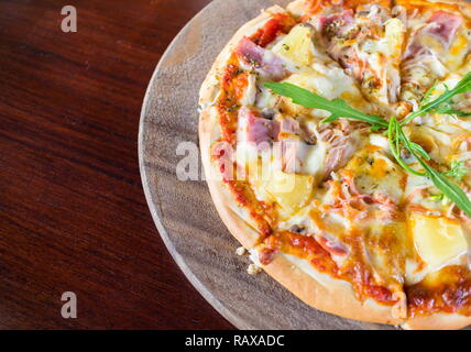 Petites tranches de pizza hawaïenne sur une planche de bois. Banque D'Images