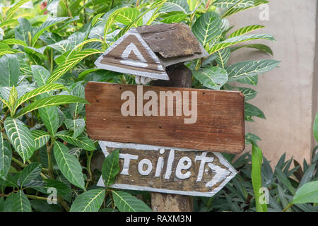 Toilettes signe dans le resort sont faits de vieux bois board sur les plantes vertes. Banque D'Images