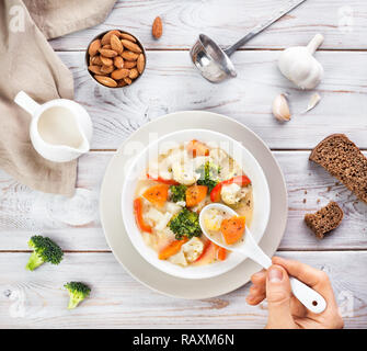 Man eating vegan soupe avec les légumes et le lait d'amande sur fond blanc en bois Banque D'Images