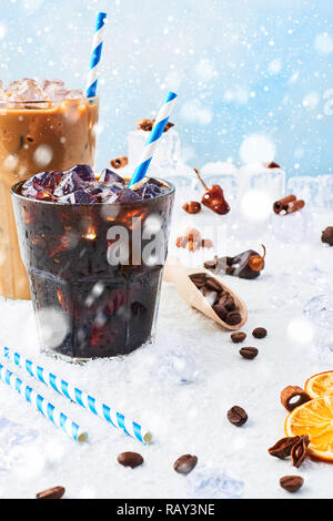 Boisson d'hiver café glacé dans un verre et de la glace à la crème de café dans un grand verre entourée de glace, les grains de café et épices diverses sur le table en marbre blanc Banque D'Images