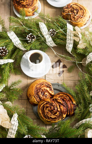 Muffins au chocolat escargot servi avec du café sur l'arrière-plan d'une couronne de branches de sapin et les cônes. Style rustique. Banque D'Images