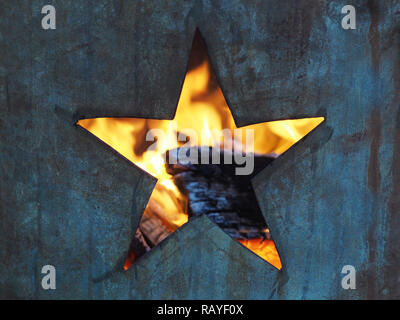 Trou dans la forme d'une étoile à cinq branches coupées en un metal burning canon à flammes et visibles à l'intérieur du bois brûlé Banque D'Images
