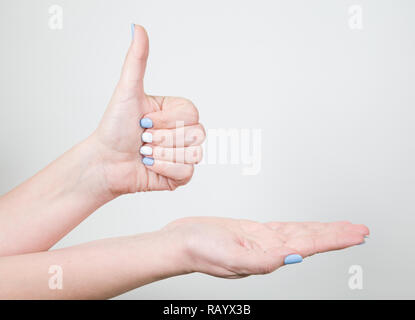 Vue rapprochée de jeunes femmes main dans la ressemblance avec des gestes thumb up isolé sur fond blanc. Les ongles avec du blanc et bleu moderne professionnel Banque D'Images