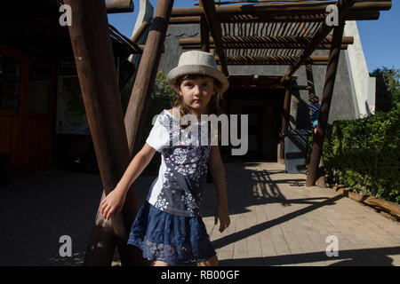 Petite fille de cinq ans, portant un chapeau, joue à l'extérieur de l'entrée de l'Addo Elephant National Park, Eastern Cape, Afrique du Sud Banque D'Images