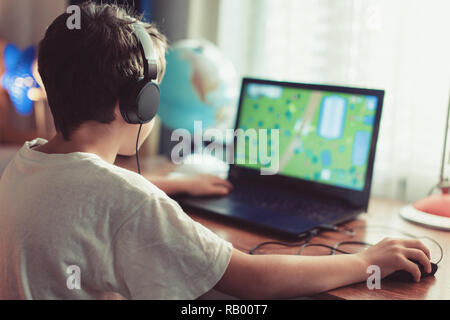 Peu tributaires gamer boy playing on laptop at home Banque D'Images