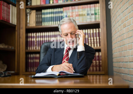 Avocat Senior businessman reading ses notes dans le home office. L'homme d'affaires occupé à parler au téléphone Banque D'Images