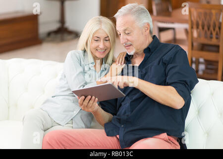 D'âge mûr à l'aide d'une tablette numérique dans leur appartement Banque D'Images