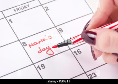 La main de femme au feutre rouge écrit mots Mamas jour de calendrier pour la fête internationale de la femme. Close up, selective focus Banque D'Images
