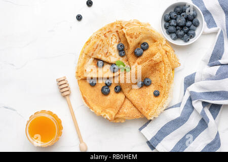 Blinis ou des crêpes avec les baies fraîches et de miel sur fond blanc, dessus de table view. L'alimentation de la Maslenitsa Banque D'Images