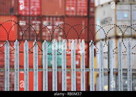 Les conteneurs d'expédition de fret fret / derrière une clôture de barbelés et de l'acier à un des ports de la mer d'affaires. Southampton, UK. Janvier 2019 Banque D'Images