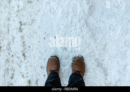 Mans les pieds dans les bottes d'hiver sur la neige fraîche. Banque D'Images