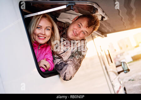 D'âge moyen mariés couple famille femme et mari sortir du véhicule récréatif caravane autocaravane fenêtre remorque looking at camera Banque D'Images