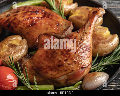 Cuisses de canard rôti avec pommes de terre, tomates dans une poêle , surface noire, Close up Banque D'Images