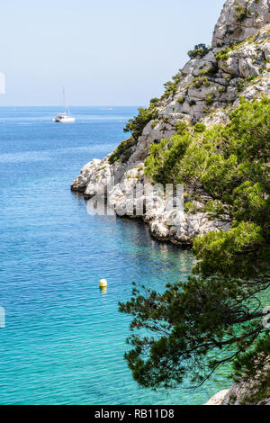 L'eau turquoise dans la calanque de Morgiou sur la côte méditerranéenne près de Marseille, en France, avec un catamaran amarre en la distance sur une journée ensoleillée. Banque D'Images