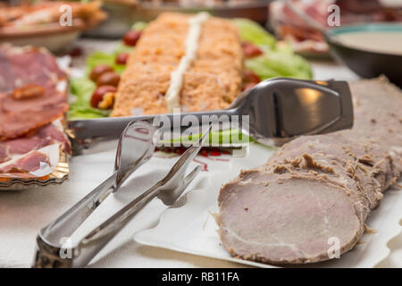 Plateaux avec différents plats de nourriture, viande, charcuterie, poisson, fruits de mer gâteau en arrière-plan, tous préparés pour un grand repas de Noël Banque D'Images