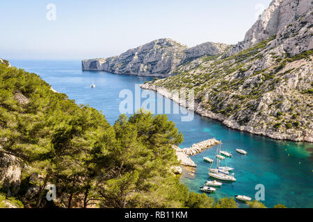Vue sur la calanque de Morgiou sur la côte méditerranéenne près de Marseille, France, avec des bateaux mouillage dans l'eau turquoise sur une journée de printemps ensoleillée. Banque D'Images