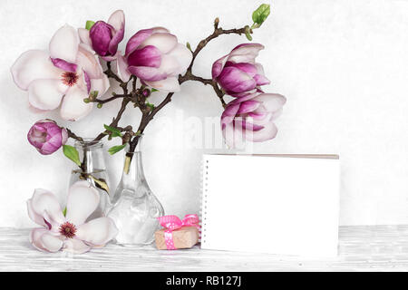 Mise en page créative faite avec des fleurs de magnolia rose, boîte cadeau et carte vide blanc sur fond de bois. maquette. nature morte.. mariage minima de printemps Banque D'Images