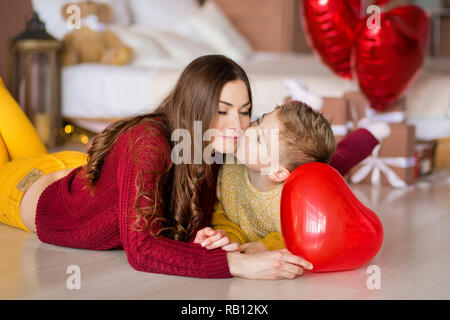 Belle jeune brunette maman mère avec son adolescent beau garçon se tenant et heureux ensemble.Femme en plumes jaunes et rouges plus doux Banque D'Images