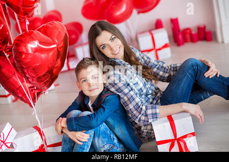 Belle jeune brunette maman mère avec son adolescent beau garçon se tenant et heureux ensemble.Femme en plumes jaunes et rouges plus doux Banque D'Images