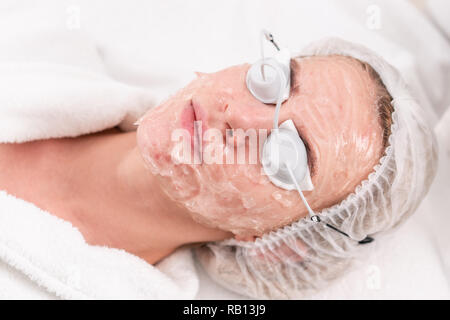 Portrait d'une jeune femme malade. La photothérapie anti acné avec du matériel professionnel. Belle femme au cours de photo rajeunissement de la procédure. Traitement pour la peau du visage à la clinique esthétique. Banque D'Images