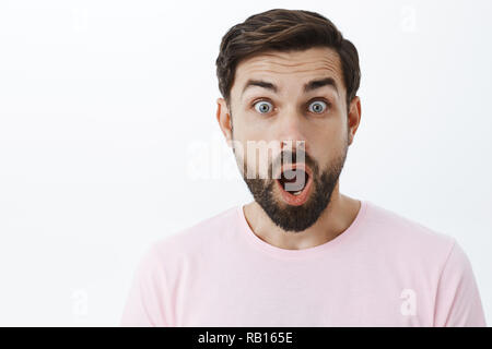 Close-up shot of impressionné et choqué stupéfié caucasian guy avec étonnement de la mâchoire tomber barbe yeux popping caméra à être surpris et excité avec nouvelle choquante sur fond gris Banque D'Images
