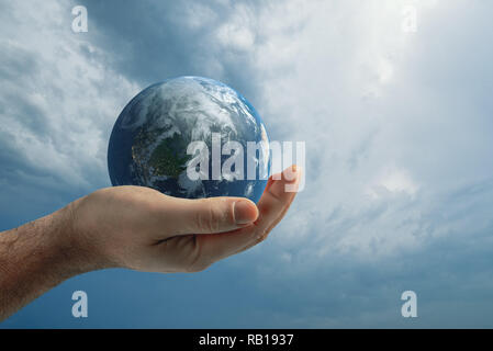 Globe dans la main de l'homme contre le ciel bleu. Concept de protection de l'environnement. Banque D'Images