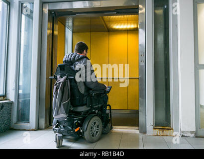 Les hommes handicapés en fauteuil roulant en allant sur ascenseur Banque D'Images