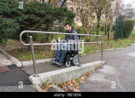 Homme en fauteuil roulant à l'aide d'une rampe à côté d'escaliers Banque D'Images