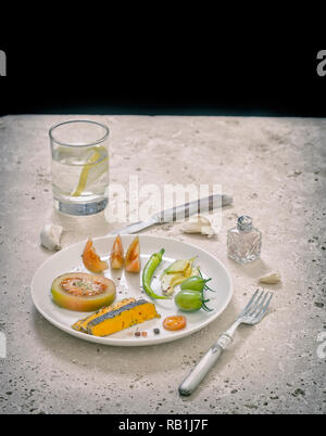 Divers légumes et fromage bleu Shropshire organisé sur plaque blanche sur rond de table rustique Banque D'Images