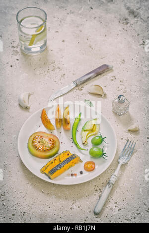 Divers légumes et fromage bleu Shropshire organisé sur plaque blanche sur rond de table rustique Banque D'Images