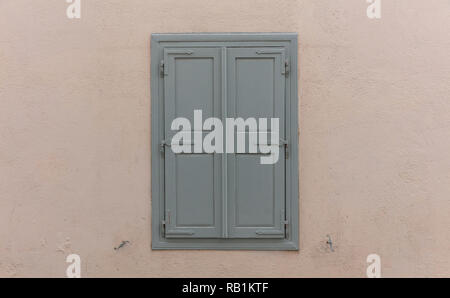 Fenêtre à l'ancienne avec des volets en bois gris, fermé, sur fond de mur peint. Façade de maison traditionnelle, de la vieille ville de Plaka, Athens Grèce Banque D'Images