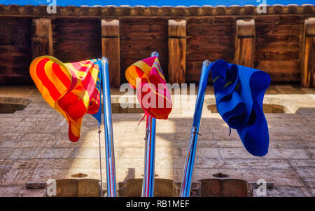 Une photo de l'horizontale de couleur rouge, jaune et bleu de l'espagnol et valencien drapeaux étendus dehors un ancien bâtiment en pierre à Valence Banque D'Images