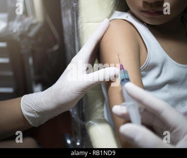Close up le médecin injecter le vaccin à la fille asiatique dans la clinique. Banque D'Images