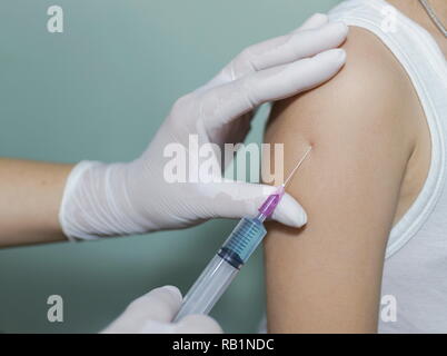 Close up le médecin injecter le vaccin à la fille asiatique dans la clinique. Banque D'Images