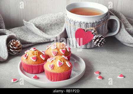 Décoré avec des coeurs muffins de sucre et une tasse avec cœur rouge sur fond gris clair. Saint Valentin ou anniversaire hiver concept. Banque D'Images